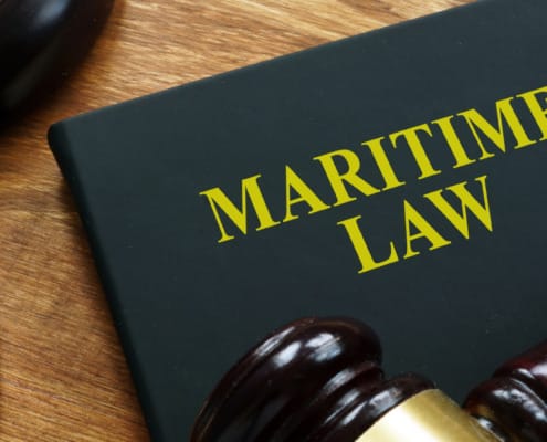 A close-up of a book titled 'Maritime Law' alongside a gavel and pen, symbolizing the impact of legal regulations on the shipping industry, including the Supreme Court's Loper Bright decision and its effects on global supply chains and maritime law.