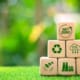 Wooden blocks representing sustainability with symbols of net zero emissions, CO2 reduction, recycling, and global environmental responsibility, highlighting the shift toward eco-friendly practices in global supply chains and contract manufacturing.